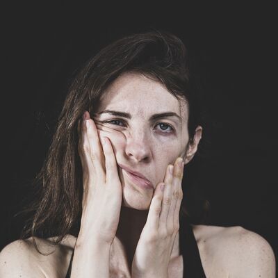 Mdchen greift sich mit Hnde ins Gesicht